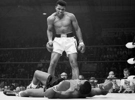 Muhammad Ali standing over Sonny Liston in the first round of their second fight in Lewiston, Maine in 1965. (Image: Getty)