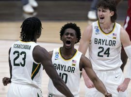 Jonathan Tchamwa Tchatchoua (23), Adam Flagler (10),) and Matthew Mayer (24) celebrate a big play down the stretch for Baylor against Arkansas in March Madness Elite 8 action. (Image: Michael Conroy/AP).